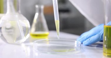 Laboratuvarda, Petri kabına motor yağı damlatan bir bilim adamı.