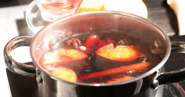 Bir kadın ocakta kepçeyle haşlanmış şarabı bardağa dolduruyor, yakın plan.