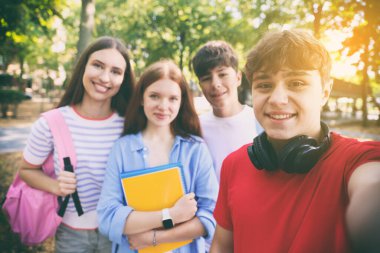 Kampüsteki öğrenciler. Genç bir çocuk arkadaşlarıyla dışarıda selfie çekiyor.