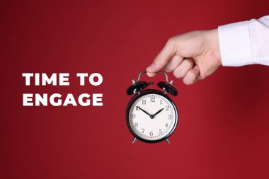 Harekete geçme zamanı. Alarm saatini kırmızı arkaplanda tutan adam, yakın plan