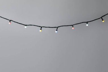 Gri arka planda parlak Noel ışıkları, yakın plan. Metin için boşluk