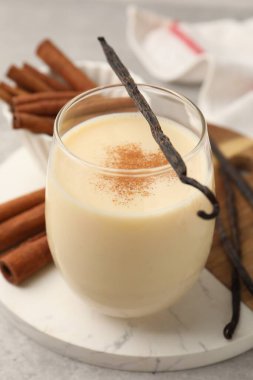 Bardakta lezzetli protein karışımı, tarçın ve vanilya kapsülleri masada, yakın plan.