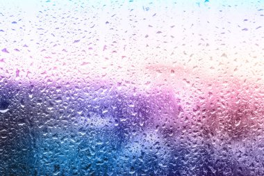 Bulanık şehir manzarası, su damlaları ile cam yüzeyden görünüm