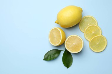 Taze limonlar ve açık mavi arka planda yapraklar, düz. Metin için boşluk
