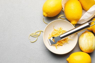 Taze limonlar, keyifli ve zester aletli gri masada, düz yerde. Metin için boşluk