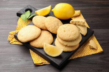 Lezzetli limonlu kurabiyeler ve koyu ahşap masadaki meyve dilimleri, yakın plan.