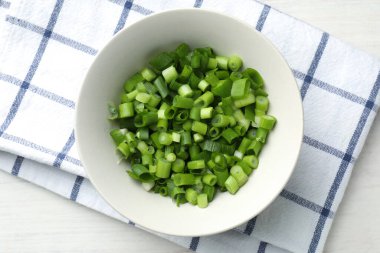 Açık ahşap masada taze soğanları kaseye koy.