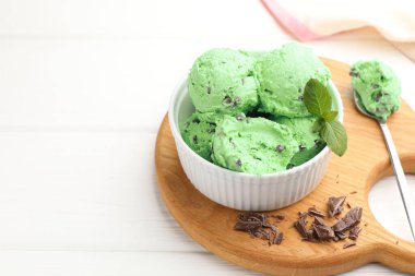 Çikolata parçalı lezzetli dondurma ve kaşık beyaz ahşap masada, yakın plan. Metin için boşluk