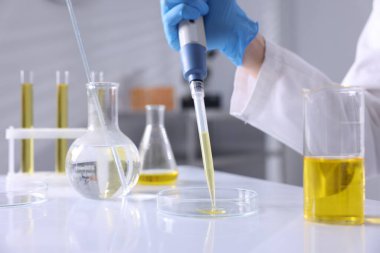 Laboratuvarda, Petri kabına motor yağı damlatan bir bilim adamı.