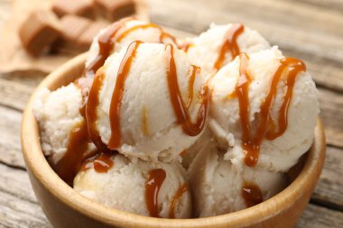 Tahta masadaki kasede karamel soslu lezzetli dondurma, yakın plan.