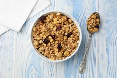 Açık mavi ahşap masada kurumuş meyveli lezzetli granola.