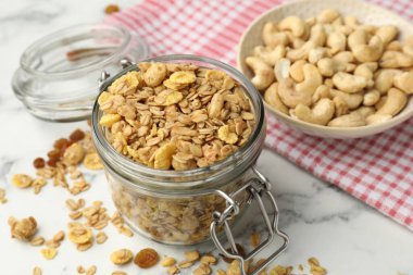 Cam kavanozdaki lezzetli granola beyaz mermer masada, yakın plan.