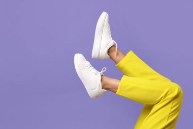 Violet 'in arka planında şık beyaz ayakkabılar giyen bir kadın, yakın plan. Metin için boşluk