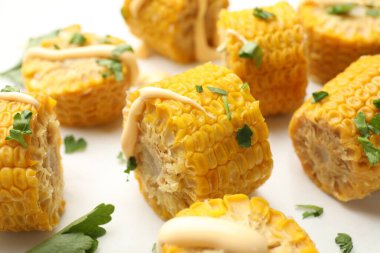 Beyaz masada maydanozlu ve soslu haşlanmış mısır koçanı parçaları.