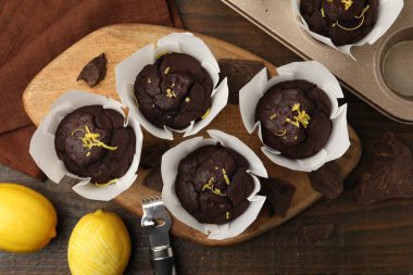 Lezzetli çikolatalı kekler, limon aromalı ve ahşap masa soyuculu, düz uzanmış.