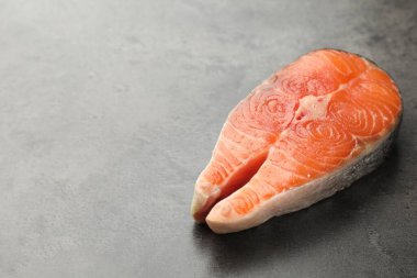 Piece of salmon fillet on gray textured table. Space for text