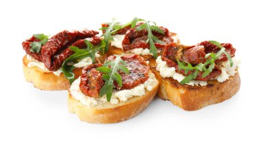 Krem peynirli lezzetli bruschettalar, güneşte kurutulmuş domatesler ve beyaz üzerine izole edilmiş roka.