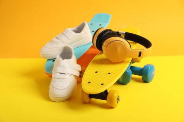 Para tahtaları, spor ayakkabıları, kulaklıklar ve spor ekipmanları sarı arka planda, yakın plan.