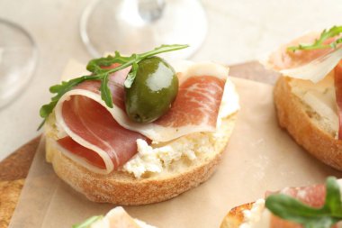 Krem peynirli nefis bruschettalar, prosciutto, yeşil zeytin ve roka masada, yakın plan.