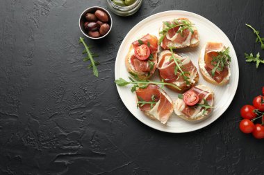 Krem peynirli nefis bruschettalar, prosciutto, domates ve roka koyu dokulu masa, düz yatak. Metin için boşluk