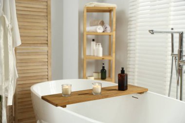 Küvette yanan mumlar ve banyoda katlanan perdeli ahşap tepsi.