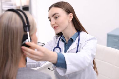 Duyma testi. Doktor klinikte hastanın işitsel kulaklığını ayarlıyor.