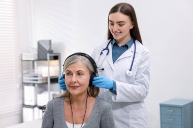 Duyma testi. Doktor klinikte hastanın işitsel kulaklığını ayarlıyor.