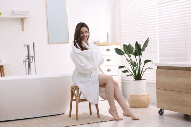 Bornozlu, göz bantlı, saçları havluyla kurutan güzel bir kadın.