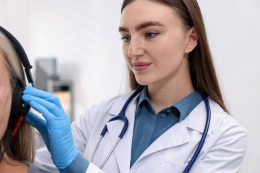 Duyma testi. Doktor klinikte hastanın işitsel kulaklıklarını ayarlıyor.