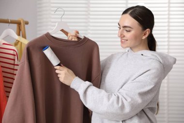 Kadın evde pamuklu bezle kazak temizliyor.