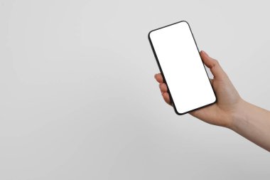 Elinde parlak arka planda boş ekranlı akıllı telefon tutan kadın, yakın plan. Tasarım için model