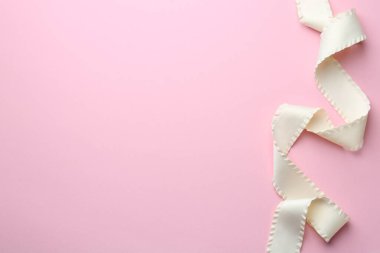 Pembe arka planda güzel bir bej kurdele, üst manzara. Metin için boşluk