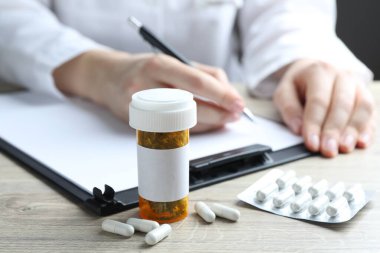 Ahşap masada çalışan doktor, kurutulmuş şifalı bitkilere ve haplara odaklan.