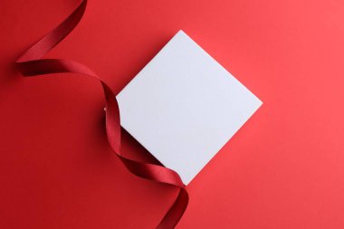 Renk arkaplan üzerinde boş kart ve kırmızı kurdele, üst görünüm. Metin için boşluk