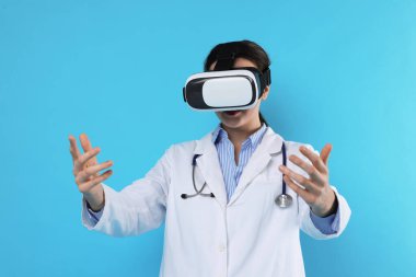 Modern teknoloji. Doktor açık mavi arka planda sanal gerçeklik kulaklığı kullanıyor