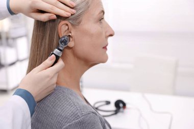 Duyma testi. Klinikte otoskopla hastanın kulağını muayene eden doktor, yakın plan. Metin için boşluk