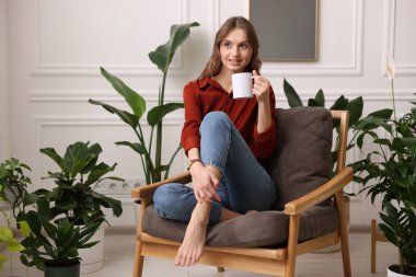 Evdeki koltukta bir fincan aromatik kahvesi olan kadın. Metin için boşluk