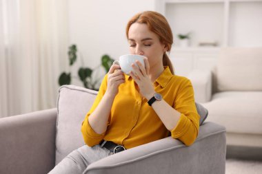 Evdeki koltukta bir fincan aromatik kahvesi olan kadın. Metin için boşluk