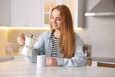 Mutfaktaki masaya sıcak kahve koyan kadın.