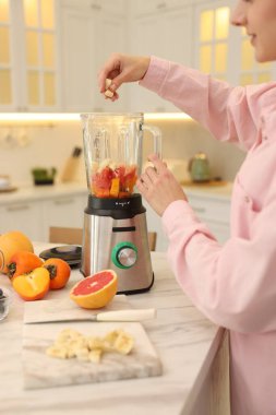 Mutfaktaki beyaz mermer masada blender ile nefis smoothie yapan kadın, yakın plan.