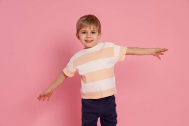 Pembe arka planda gülümseyen küçük çocuğun portresi