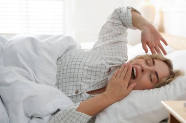 Evde yatakta esneyen bir kadın. Günaydın.