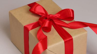 Hediye kutusunda kırmızı kurdele takan bir kadın, yakın plan. Hafif arkaplan