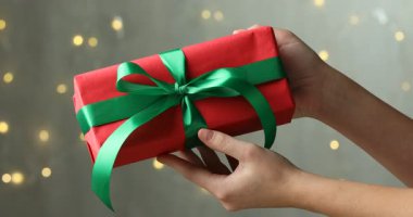 Güzel bir Noel hediyesi kutusu tutan bir kadın. Arka planda bulanık ışıklar, yakın plan.