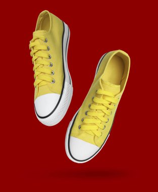Yellow sneakers in air on red background