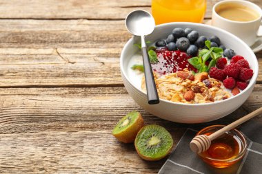 Sağlıklı kahvaltı. Fındıklı yulaf ezmesi, böğürtlen ve yoğurt ahşap masada, yakın plan. Metin için boşluk