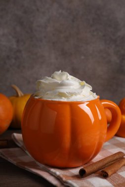 Balkabaklı latte, çırpılmış krema ve ahşap masada tarçın çubukları, yakın plan.