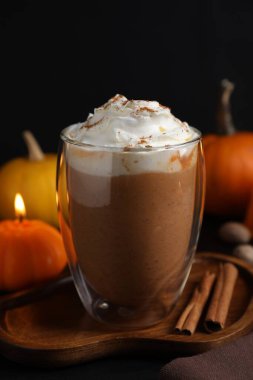 Krem şantili balkabaklı latte ve siyah arka planda sonbahar dekoru, yakın plan.
