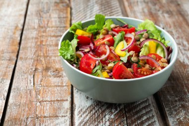 Mercimekli lezzetli salata ve ahşap masadaki kasede sebzeler, yakın plan. Metin için boşluk