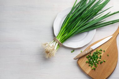 Taze taze yeşil soğan ve beyaz ahşap masa üzerinde bıçak, düz. Metin için boşluk